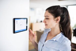 woman looking at a smart thermostat on wall